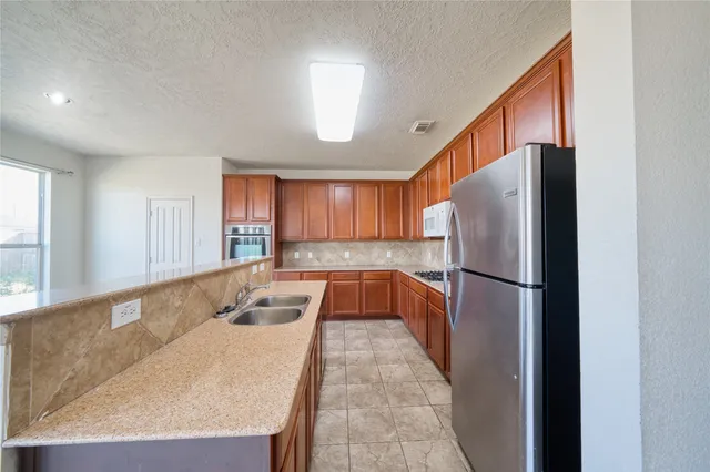 a kitchen with stainless steel appliances granite countertop a refrigerator a sink and a stove