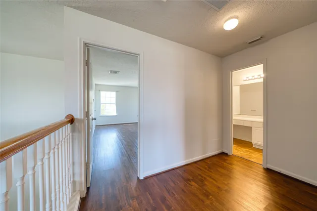 a view of a hallway to room with wooden floor