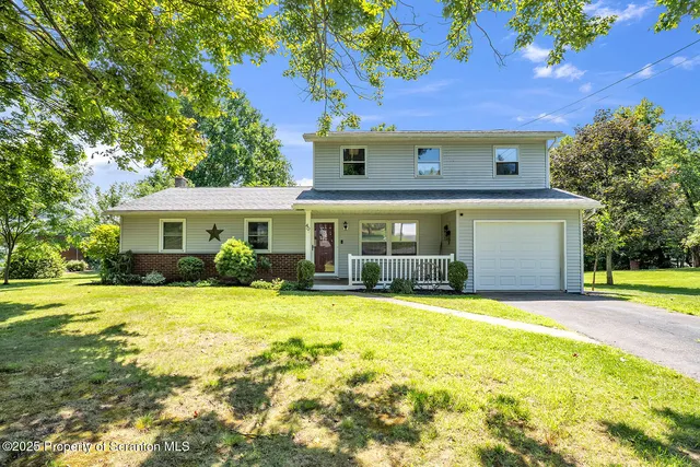 a front view of a house with a yard and trees