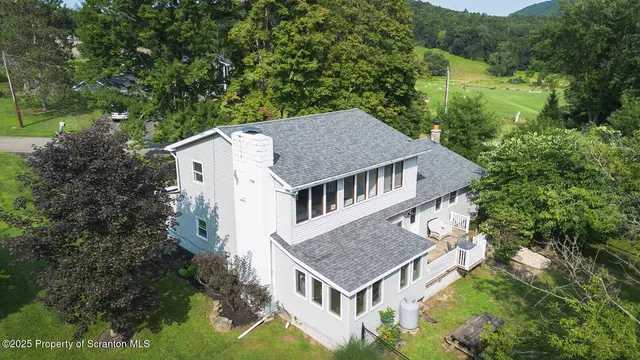 an aerial view of residential house with outdoor space and trees all around
