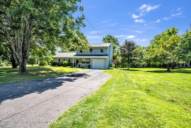 a front view of a house with yard and green space