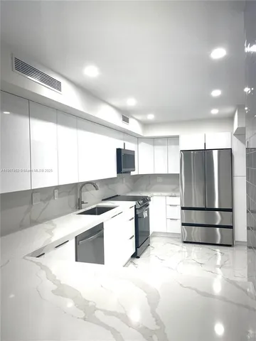 a kitchen with stainless steel appliances kitchen island granite countertop a refrigerator and a stove top oven