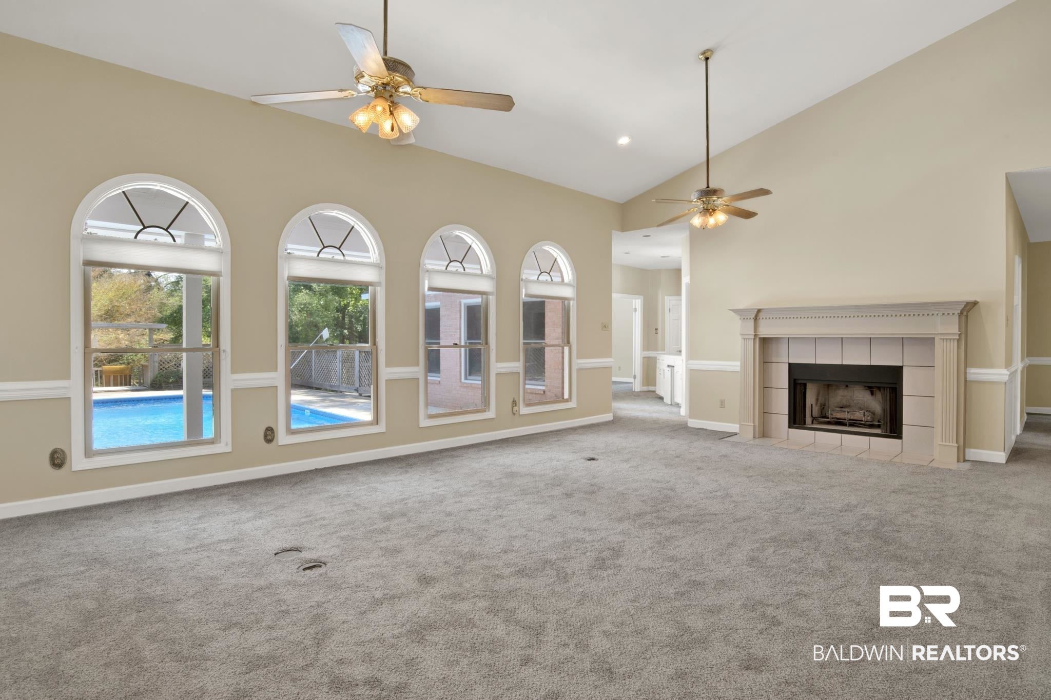 6805 Hunters Court Mobile, AL 36695 - Photo 8 of 37 Unfurnished living room featuring a ceiling fan, vaulted ceiling, carpet floors, a tiled fireplace, and baseboards