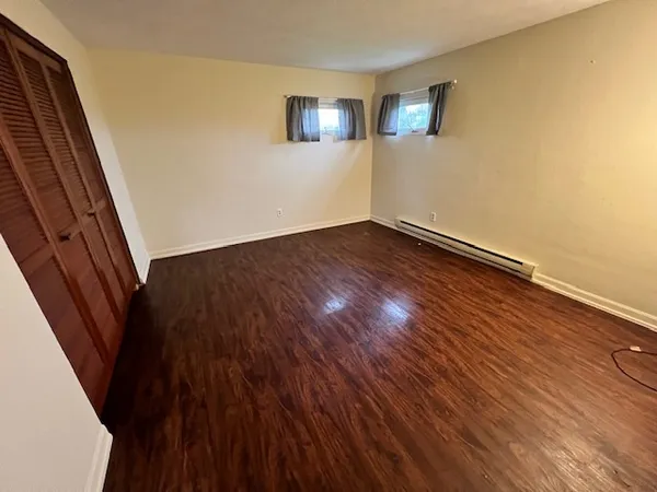 a view of an empty room with wooden floor and stairs