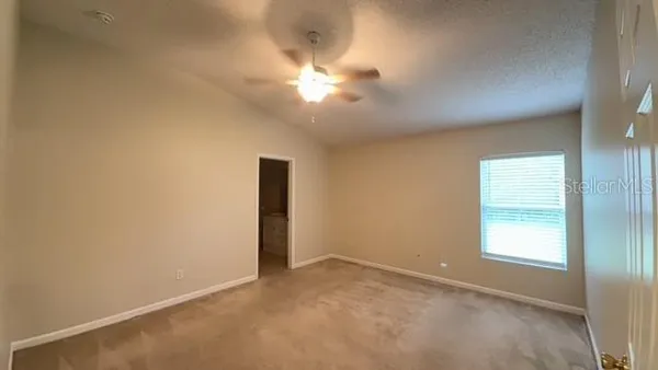 an empty room with a chandelier fan and windows