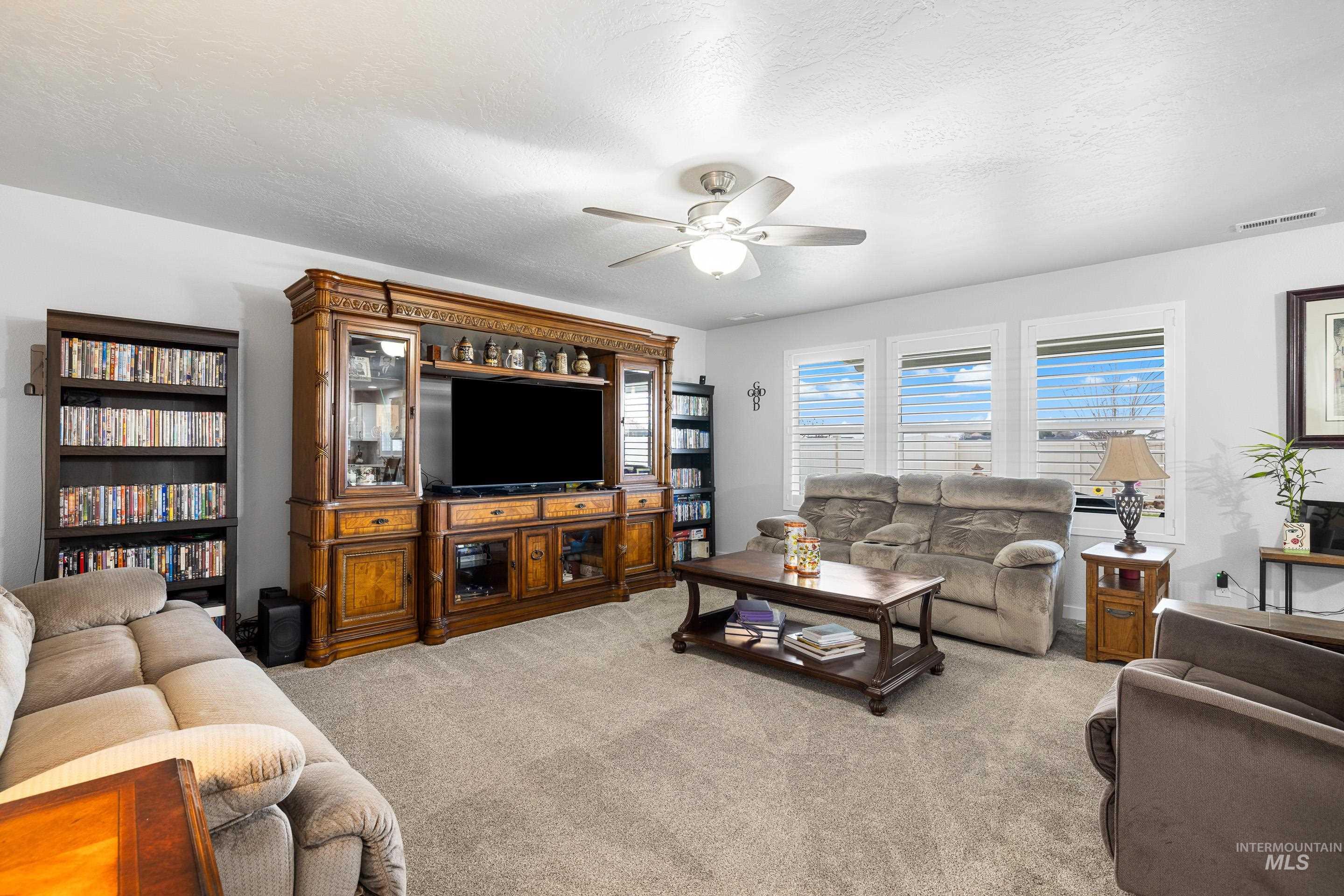 3308 West Zarea Drive Meridian, ID 83642 - Photo 13 of 47 Living area featuring a textured ceiling, light carpet, and ceiling fan