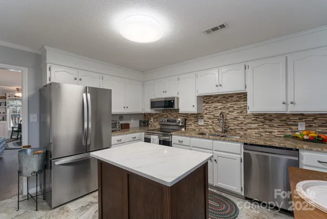 a kitchen with a refrigerator a sink a stove a microwave and cabinets