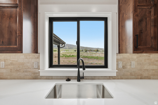 2970 North Mahogany Vly Road Logan, UT 84341 - Photo 9 of 39 Kitchen view of backsplash, dark wood finish cabinets, and light stone countertops