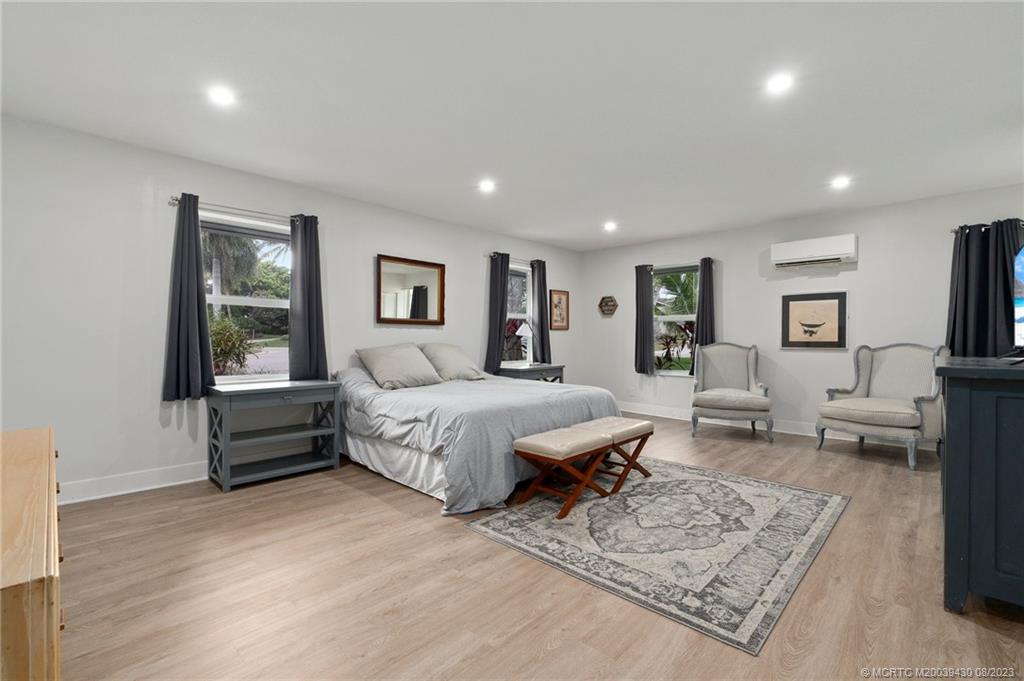 40 North River Road Stuart, FL 34996 - Photo 28 of 51 a spacious bedroom with a bed a couch and a dresser with wooden floor