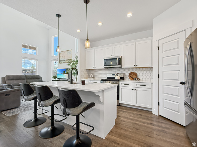 641 Desert Willow Drive Mapleton, UT 84664 - Photo 41 of 41 Kitchen featuring a breakfast bar, open floor plan, white cabinets, stainless steel appliances, and dark wood-style floors
