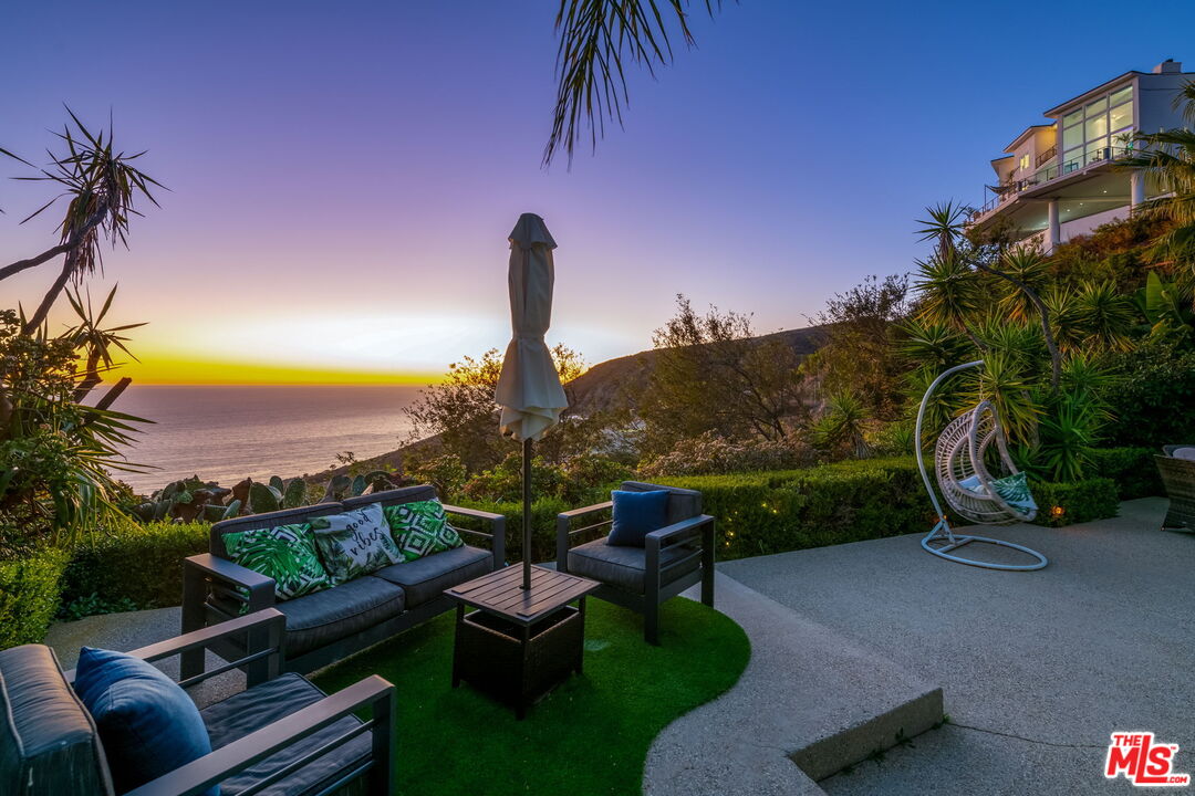 31518 Anacapa View Drive Malibu, CA 90265 - Photo 51 of 75 a view of a patio with couches table and chairs under an umbrella