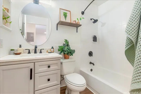 a bathroom with a sink a toilet a mirror a vanity a bath tub and shower
