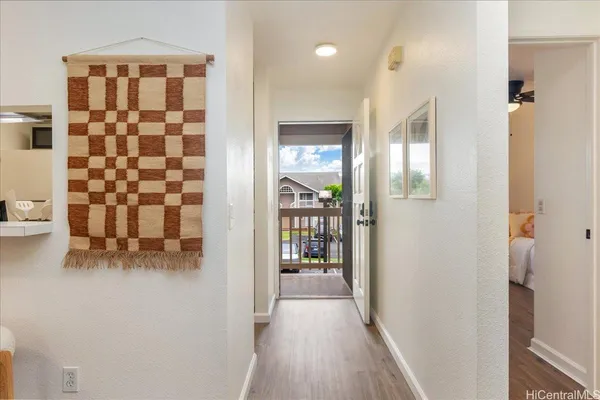 a view of a hallway with wooden floor and a bathroom