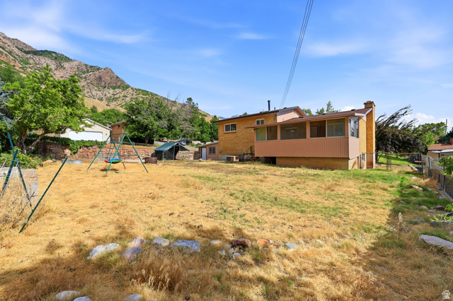 1486 3rd Street Ogden, UT 84404 - Photo 23 of 26 Spacious backyard featuring an elevated enclosed patio, brick exterior, and a prominent mountainous backdrop