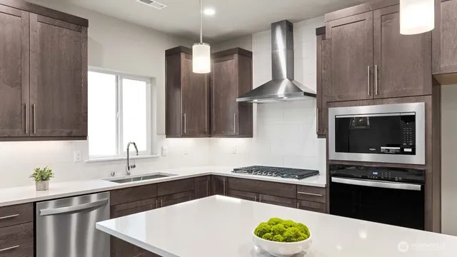 a kitchen with stainless steel appliances kitchen island granite countertop a sink a stove and a refrigerator
