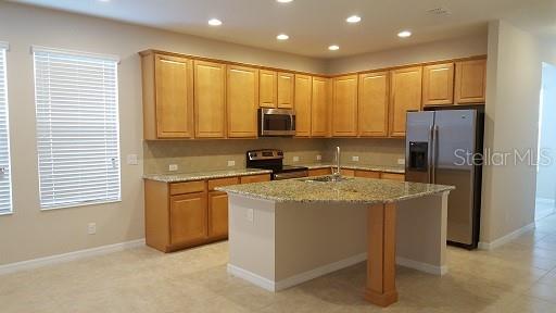 7652 Ripplepointe Way Windermere, FL 34786 - Photo 6 of 21 a kitchen with stainless steel appliances granite countertop a stove a refrigerator and a microwave