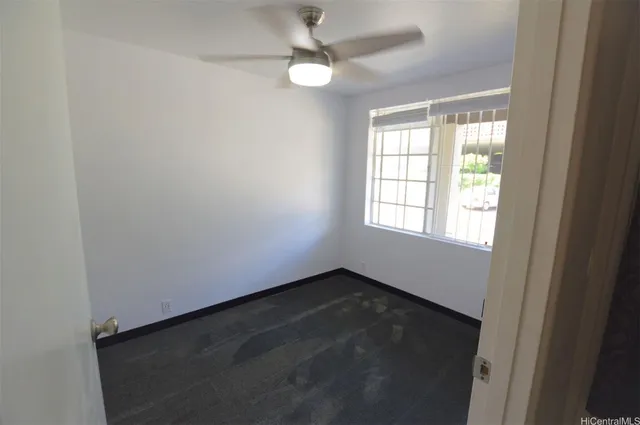 an empty room with a window and a fan