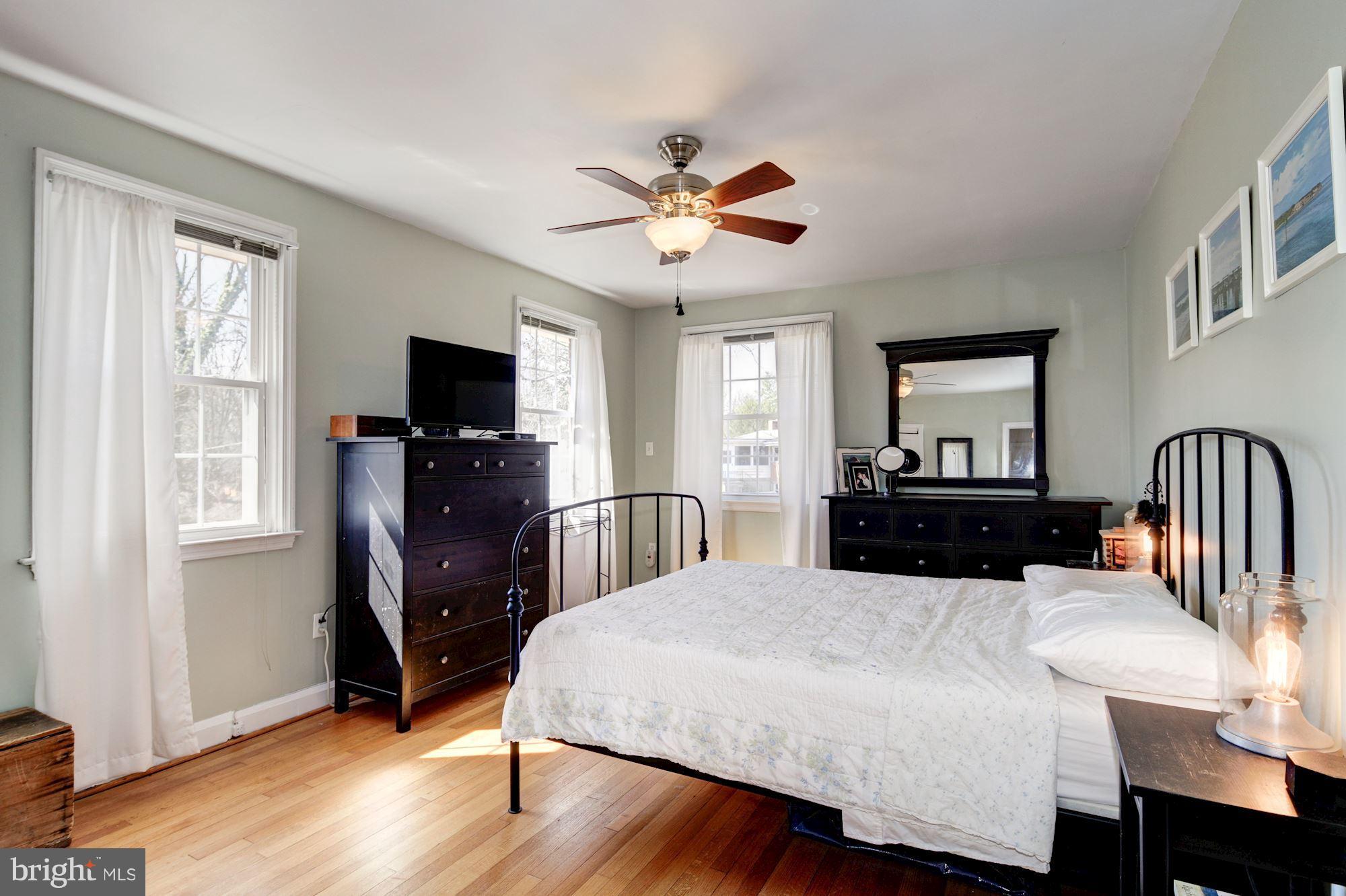 6722 Sherwood Road Baltimore, MD 21239 - Photo 17 of 30 a large bedroom with wooden floor a bed and a flat screen television