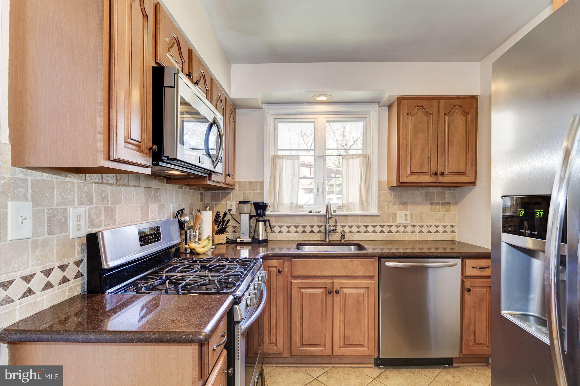 6722 Sherwood Road Baltimore, MD 21239 - Photo 8 of 30 a kitchen with stainless steel appliances granite countertop a stove a sink dishwasher and cabinets with wooden floor