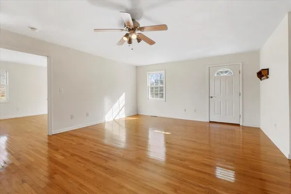 a view of an empty room with wooden floor and a window