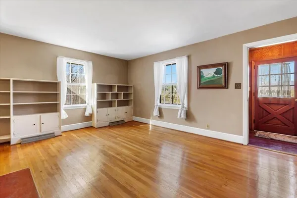 an empty room with wooden floor fireplace and windows