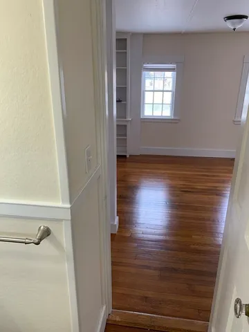 a view of empty room with window and wooden floor
