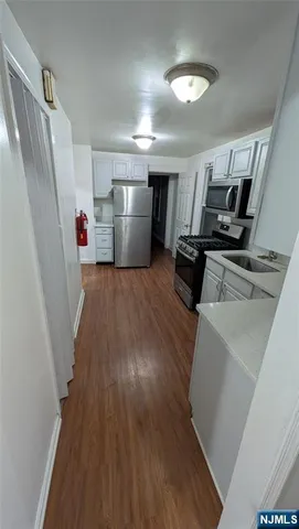 a kitchen with sink a refrigerator and wooden floor