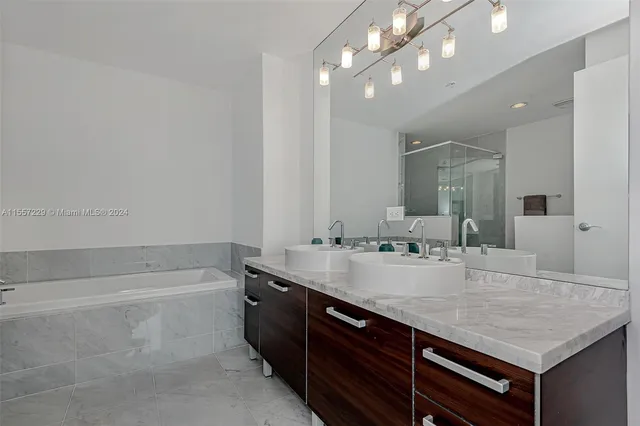 a bathroom with a granite countertop sink a large mirror and shower
