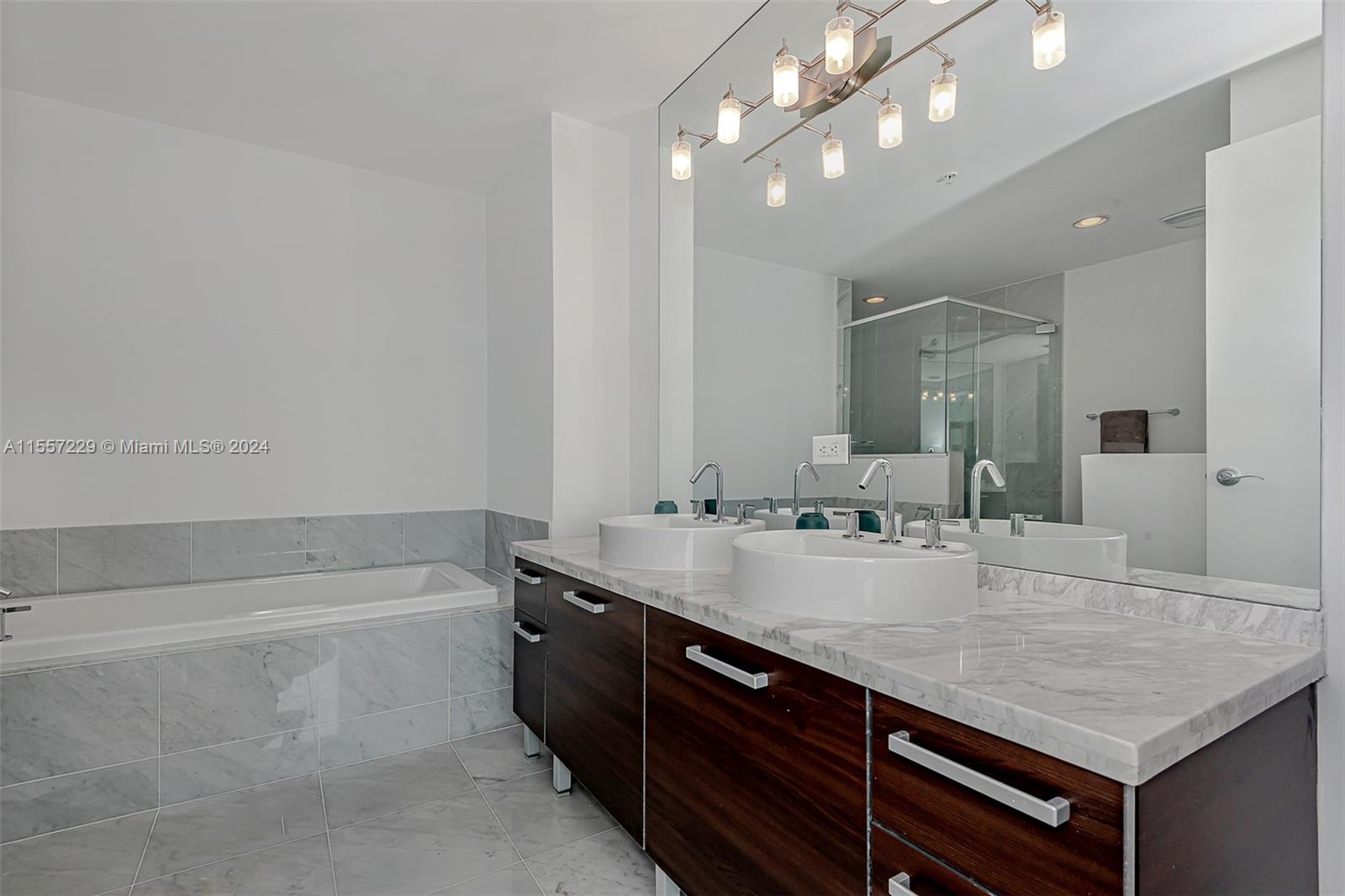 244 Biscayne Boulevard, Unit UPH4907 Miami, FL 33132 - Photo 13 of 38 a bathroom with a granite countertop sink a large mirror and shower