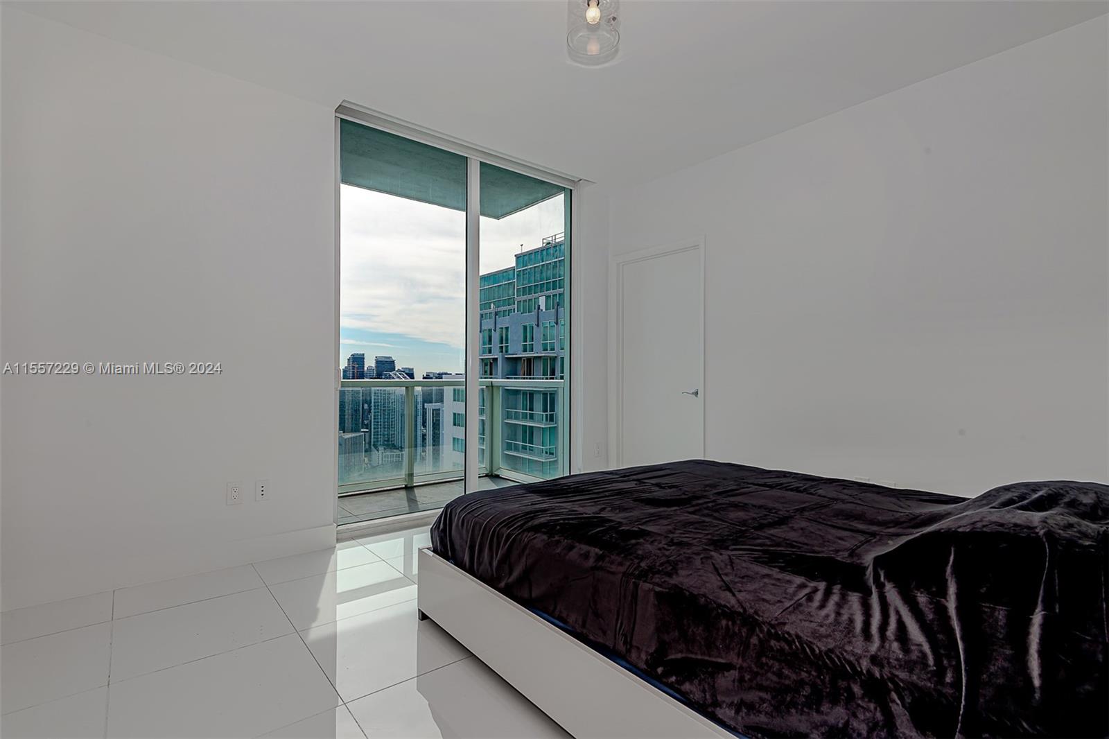 244 Biscayne Boulevard, Unit UPH4907 Miami, FL 33132 - Photo 33 of 38 a bedroom with a bed and glass door