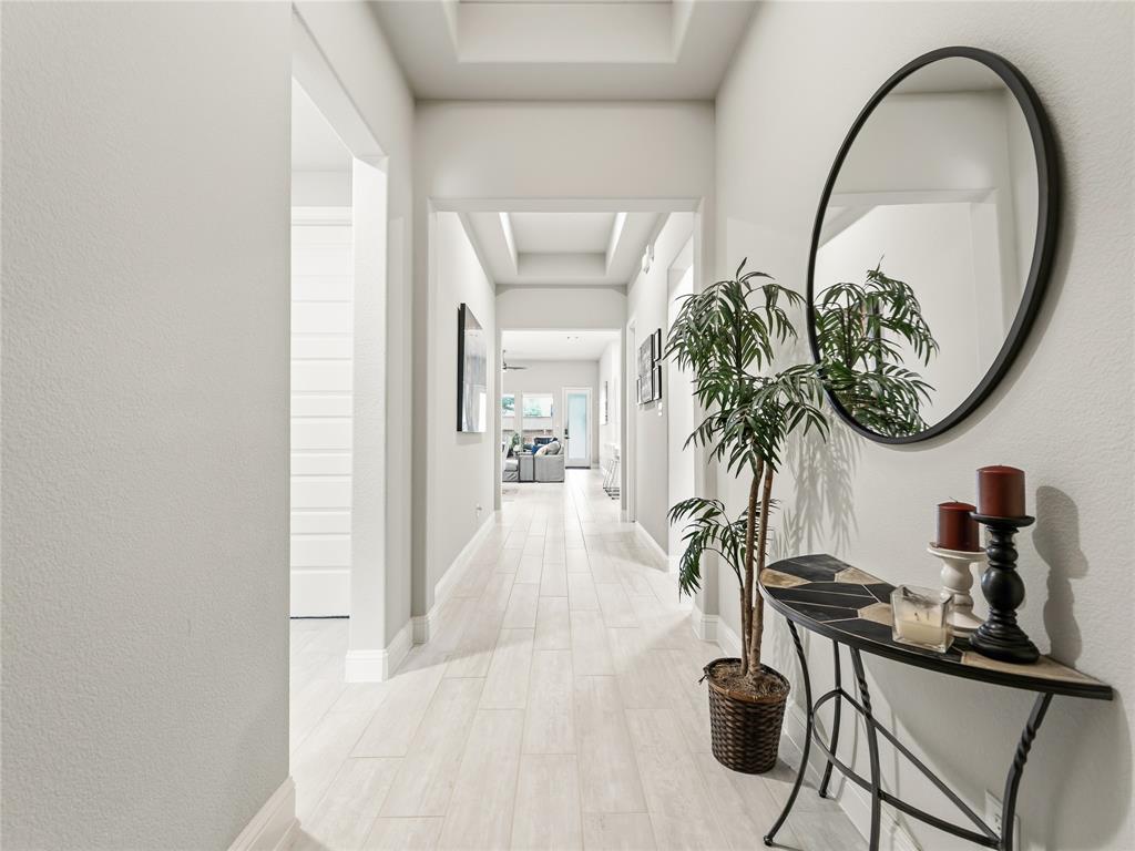 15340 Crape Myrtle Road Frisco, TX 75035 - Photo 2 of 40 Hallway featuring light wood-finish flooring, white baseboards, and a tray ceiling