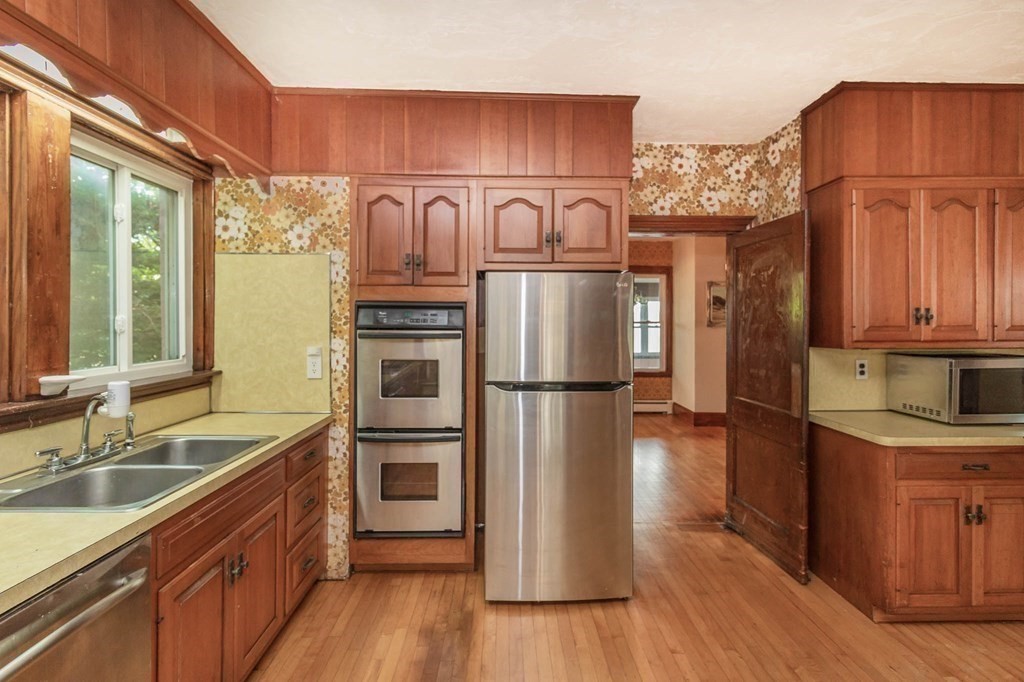 91 Edgewater Road Hull, MA 02045 - Photo 15 of 41 a kitchen with stainless steel appliances granite countertop a refrigerator a stove a sink dishwasher and wooden cabinets with wooden floor