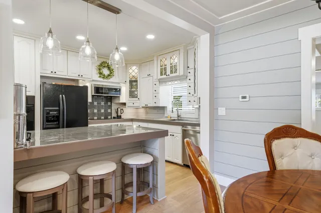 a kitchen with stainless steel appliances granite countertop a table chairs sink and cabinets