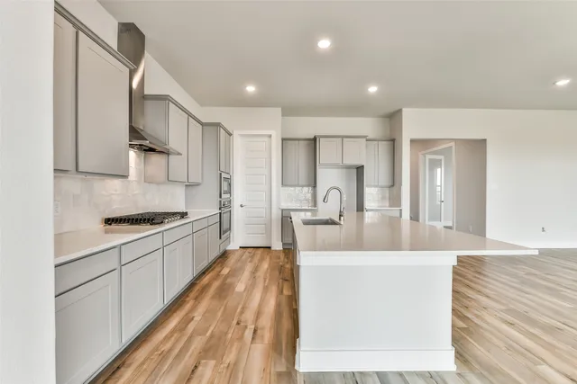 a large kitchen with stainless steel appliances granite countertop a lot of counter space and wooden floors