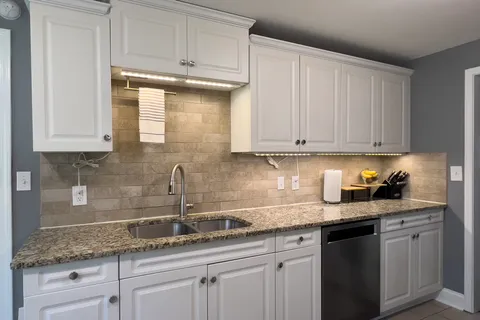 a kitchen with granite countertop white cabinets and a sink