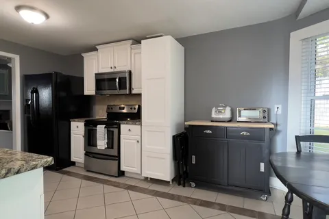 a kitchen with granite countertop a refrigerator and a stove top oven