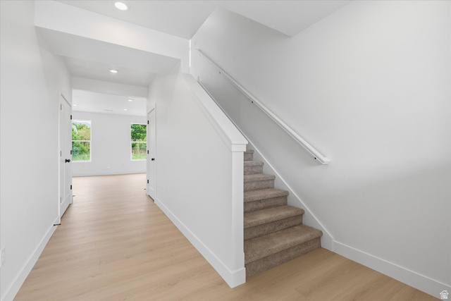 844 North 400 West Logan, UT 84321 - Photo 15 of 43 Bright entryway featuring wood-finish flooring, recessed lighting, and a staircase with carpeted treads and a white handrail