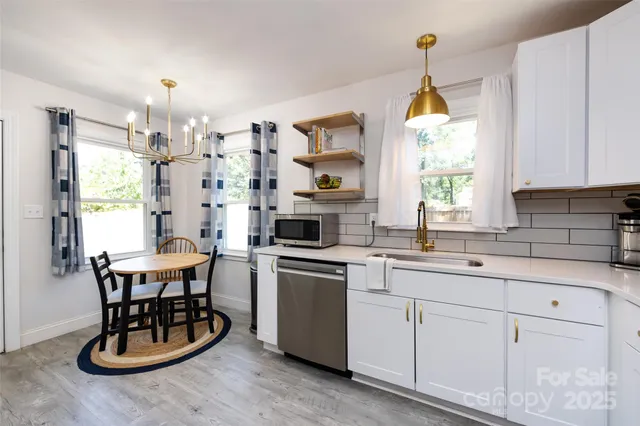 a kitchen with a sink stove and white cabinets with wooden floor