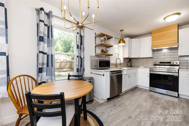 a kitchen with a table chairs stove and white kitchen