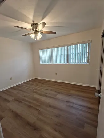 a view of an empty room with window and wooden floor
