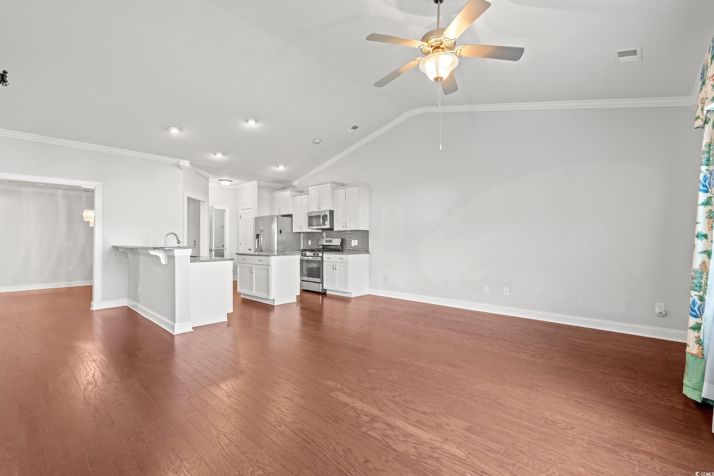 135 Parmelee Drive, Unit C Murrells Inlet, SC 29576 - Photo 11 of 37 Unfurnished living room featuring ornamental molding, vaulted ceiling, dark wood-style floors, recessed lighting, and ceiling fan