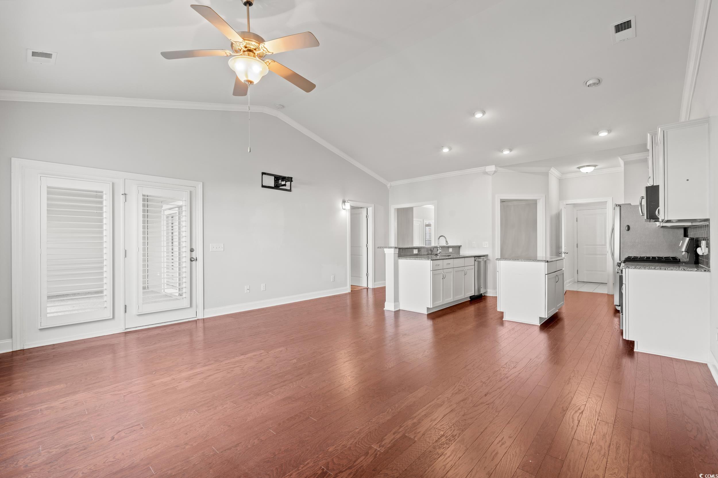 135 Parmelee Drive, Unit C Murrells Inlet, SC 29576 - Photo 12 of 37 Unfurnished living room with ornamental molding, dark wood-type flooring, vaulted ceiling, and a ceiling fan