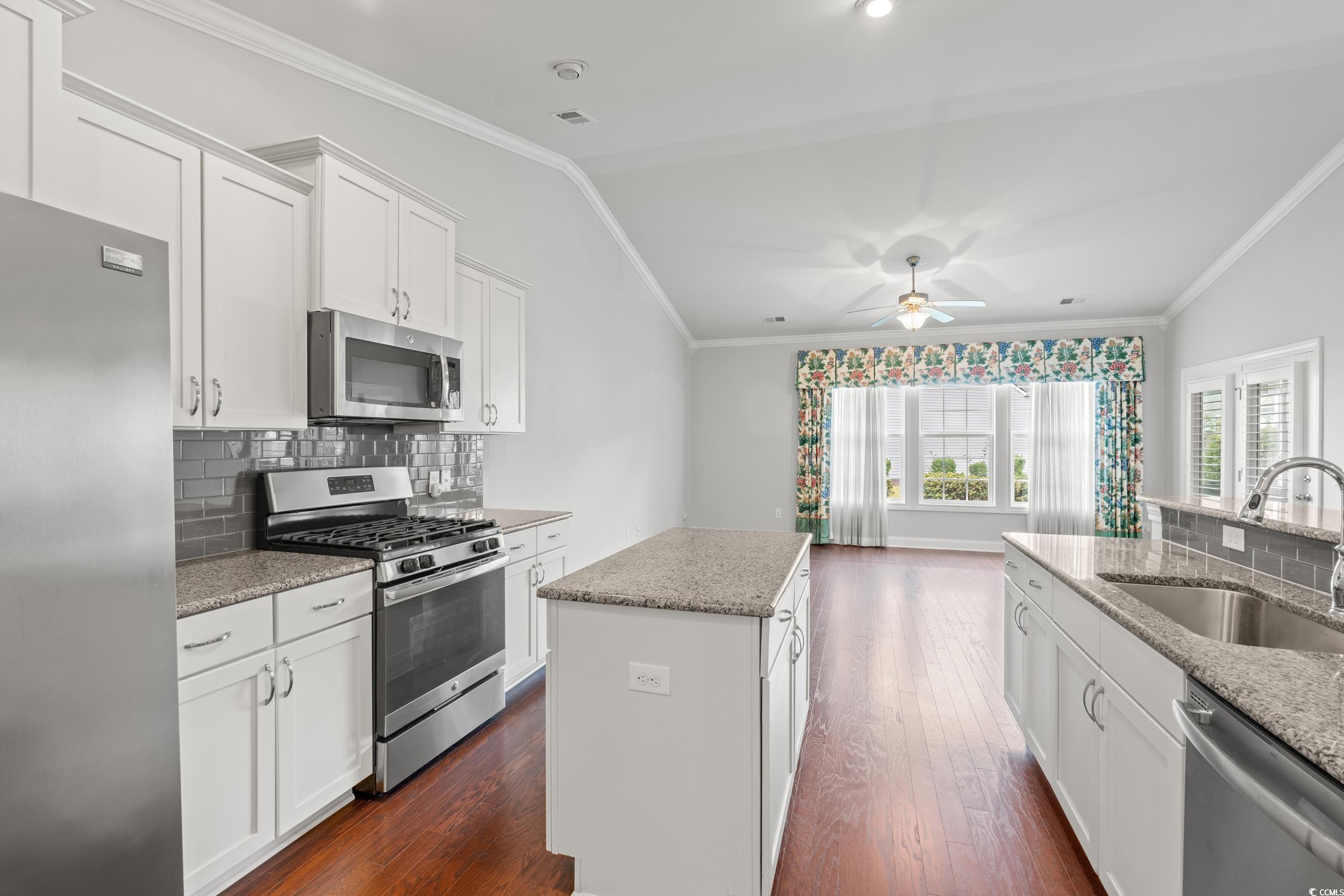 135 Parmelee Drive, Unit C Murrells Inlet, SC 29576 - Photo 13 of 37 Kitchen with backsplash, white cabinets, stainless steel appliances, ornamental molding, and dark wood finished floors
