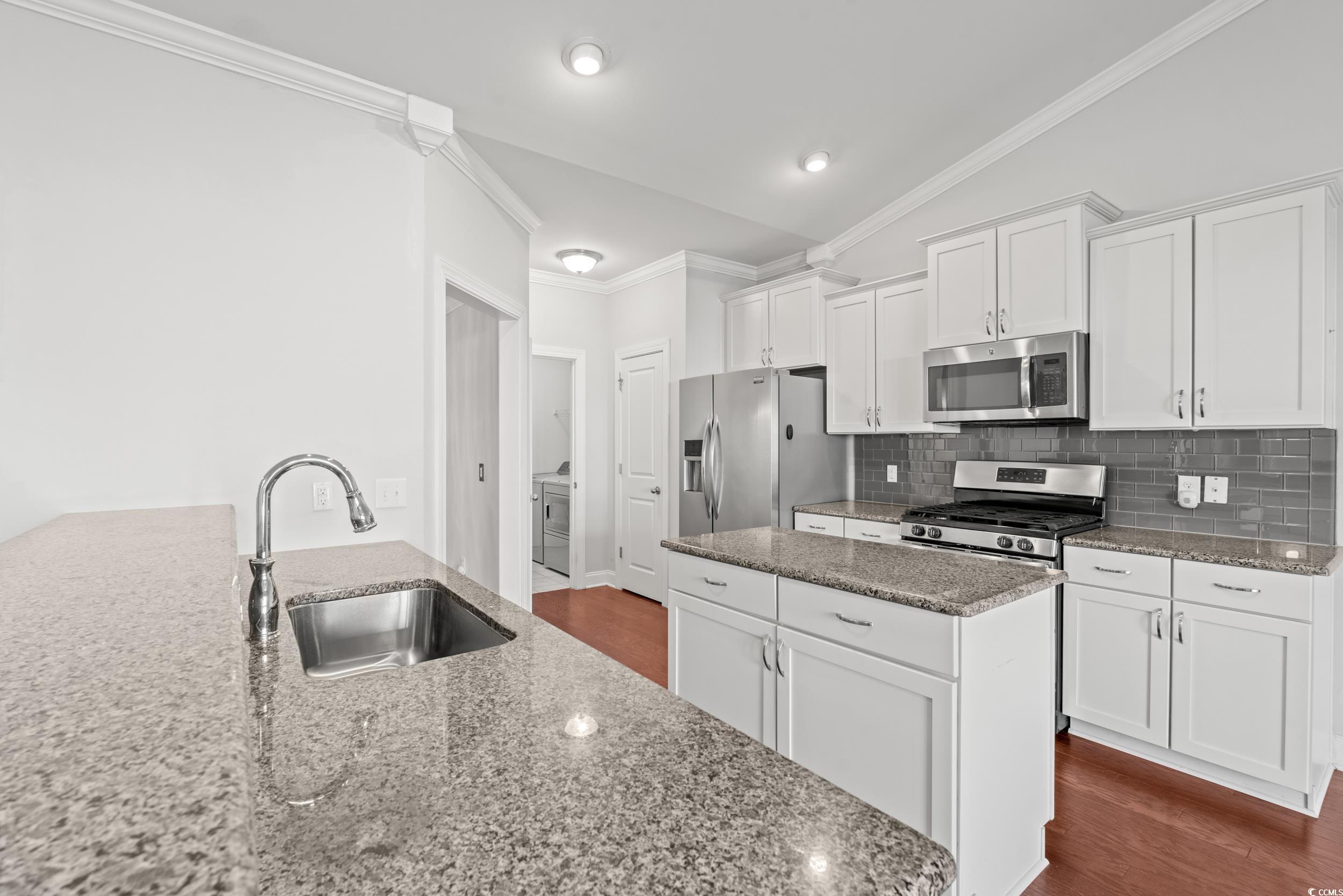 135 Parmelee Drive, Unit C Murrells Inlet, SC 29576 - Photo 14 of 37 Kitchen with crown molding, white cabinets, dark wood finished floors, stainless steel appliances, and decorative backsplash