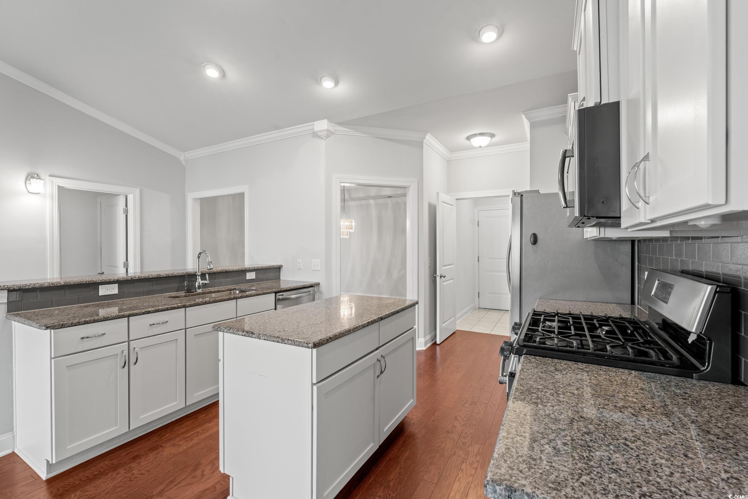 135 Parmelee Drive, Unit C Murrells Inlet, SC 29576 - Photo 15 of 37 Kitchen with white cabinets, crown molding, appliances with stainless steel finishes, a center island, and decorative backsplash