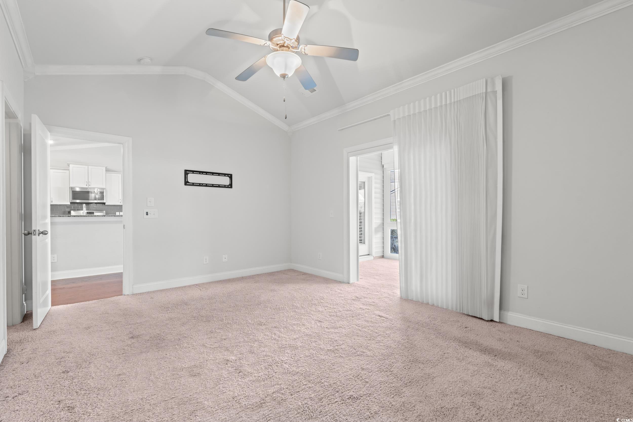 135 Parmelee Drive, Unit C Murrells Inlet, SC 29576 - Photo 18 of 37 Unfurnished living room with vaulted ceiling, ornamental molding, light carpet, and ceiling fan