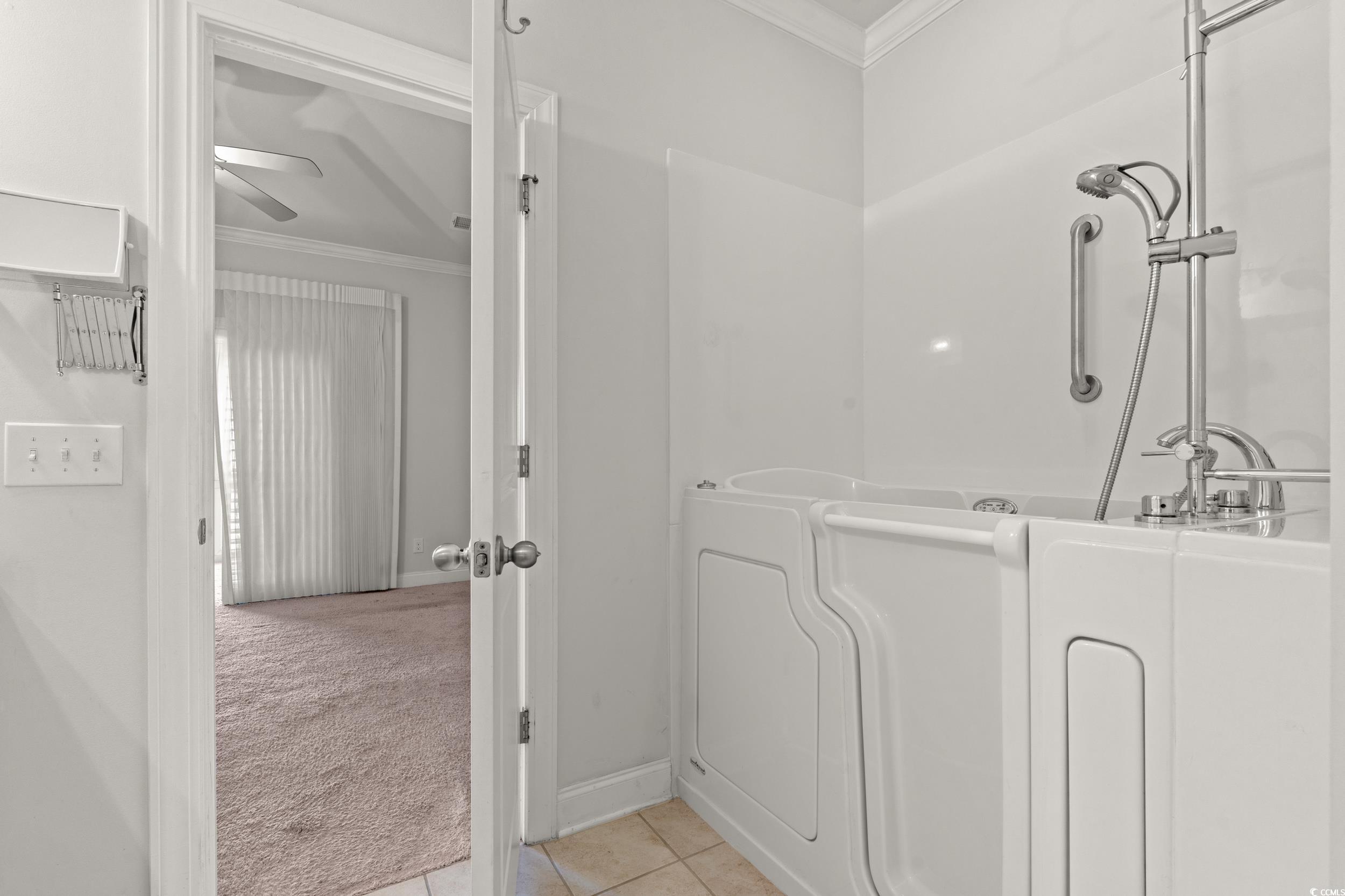 135 Parmelee Drive, Unit C Murrells Inlet, SC 29576 - Photo 22 of 37 Full bath with crown molding, light carpet, light tile patterned floors, a bathtub, and a ceiling fan