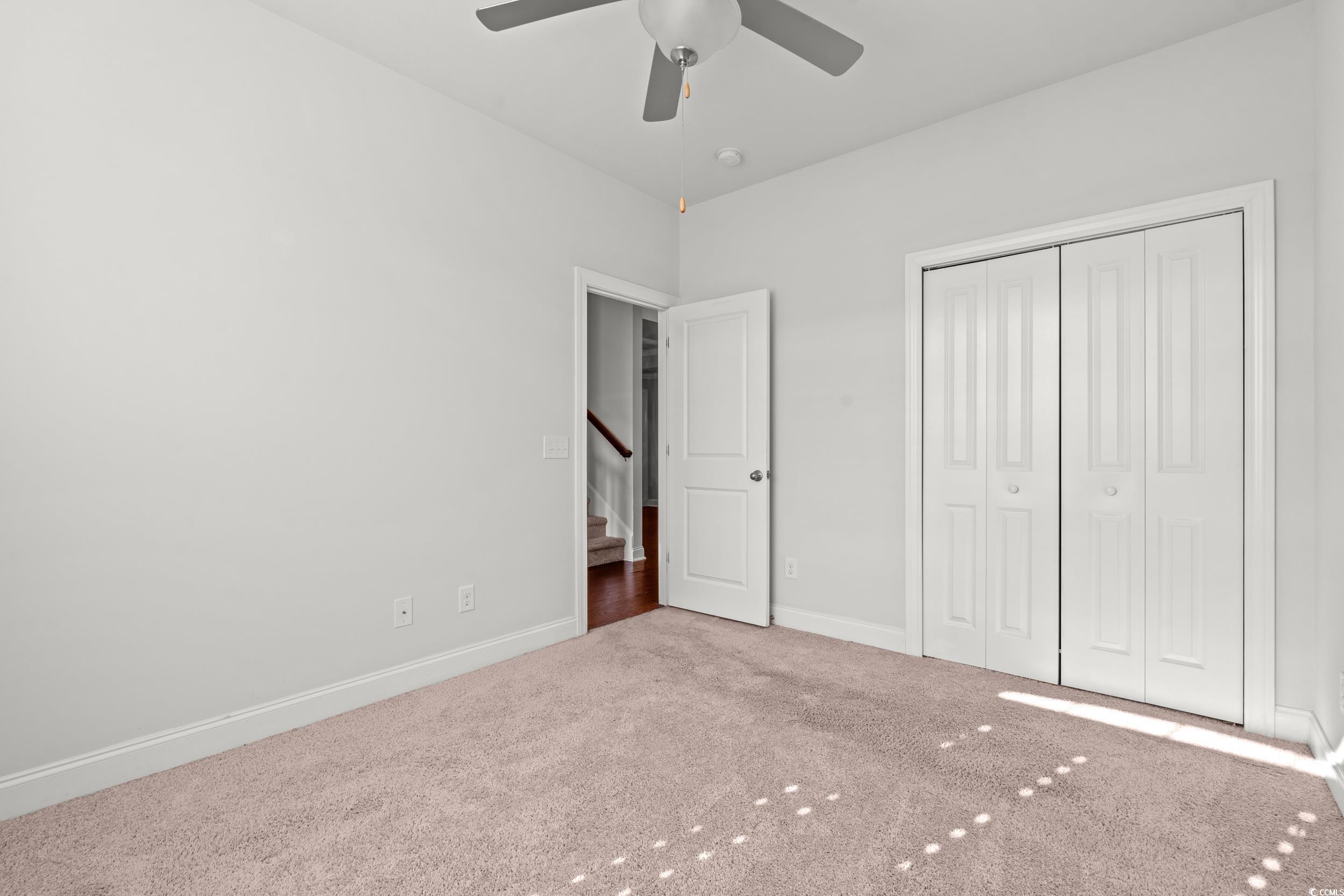 135 Parmelee Drive, Unit C Murrells Inlet, SC 29576 - Photo 5 of 37 Unfurnished bedroom featuring carpet, a closet, and ceiling fan