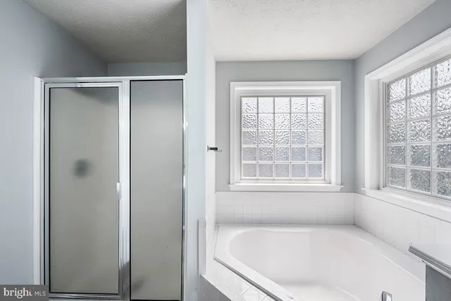 an empty room with wooden floor a ceiling fan and windows