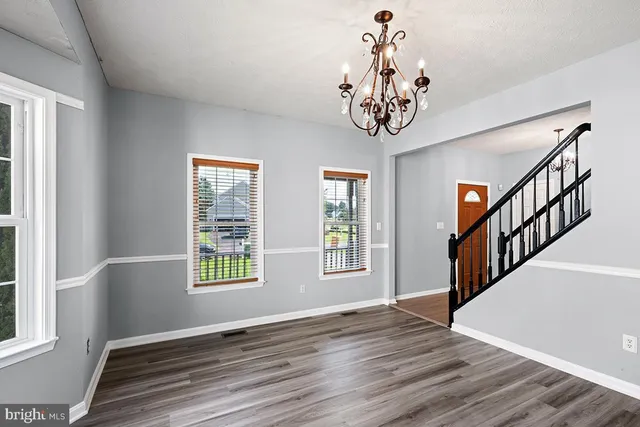 a view of an empty room with wooden floor fireplace and a window